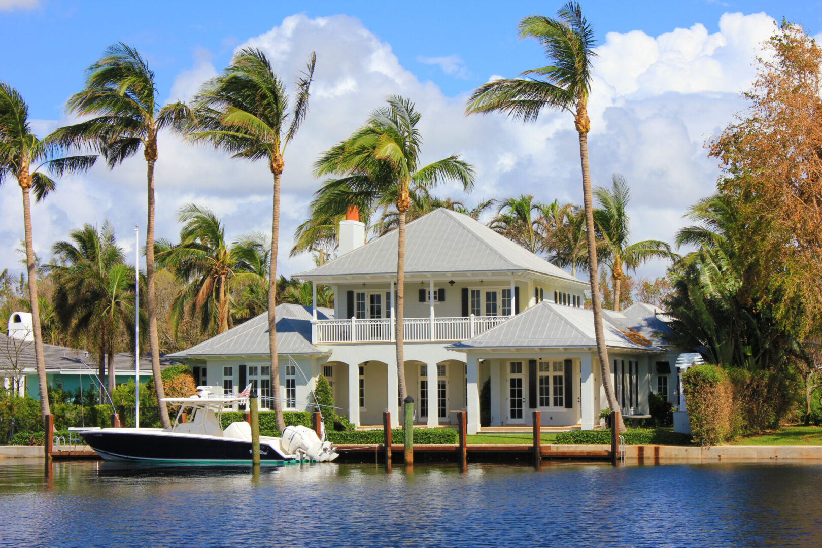 A house with palm trees and boats in the water.