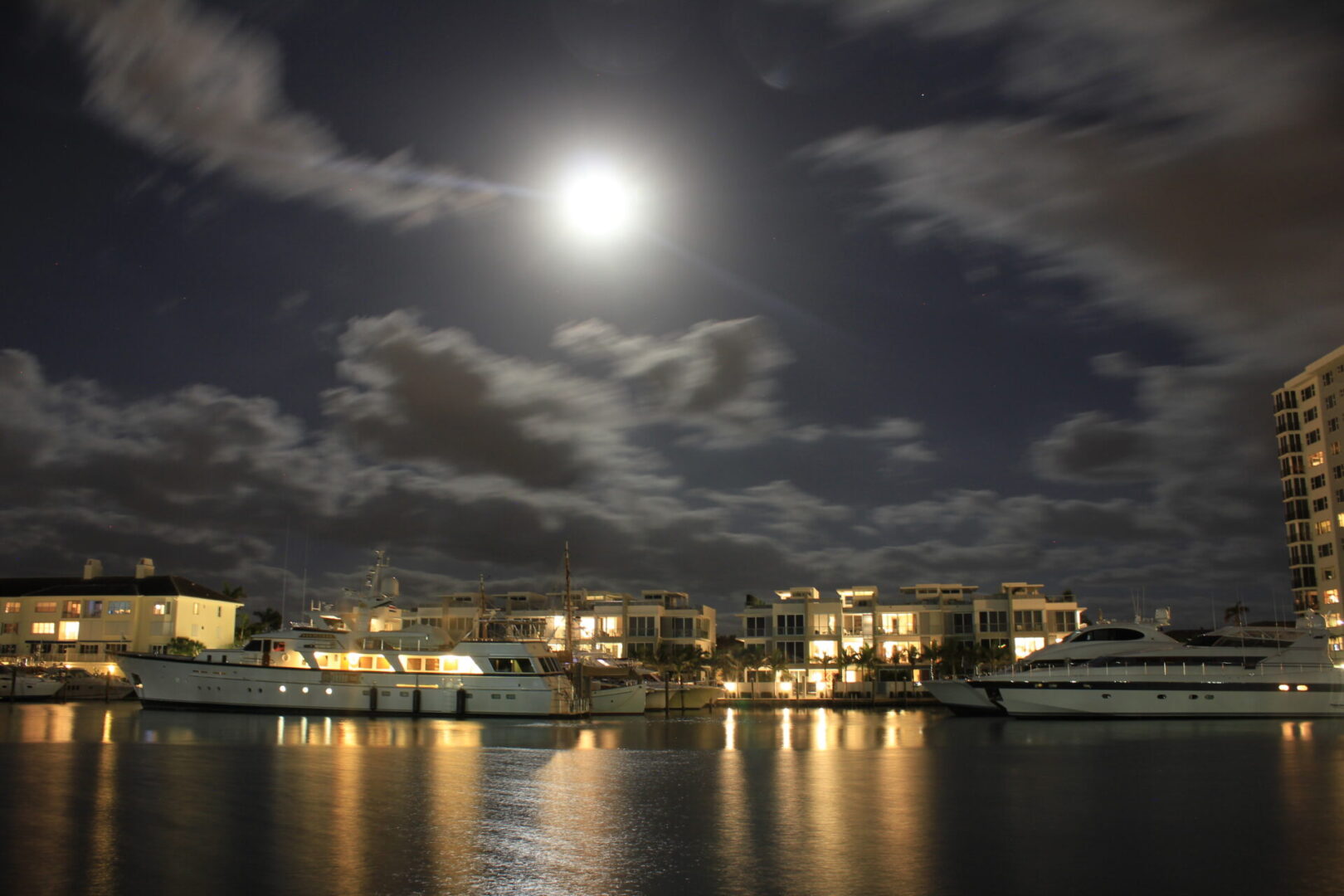 A full moon over the water and buildings.